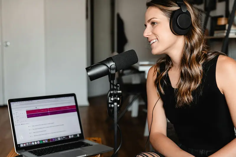 A podcast host recording an episode with a laptop and microphone
